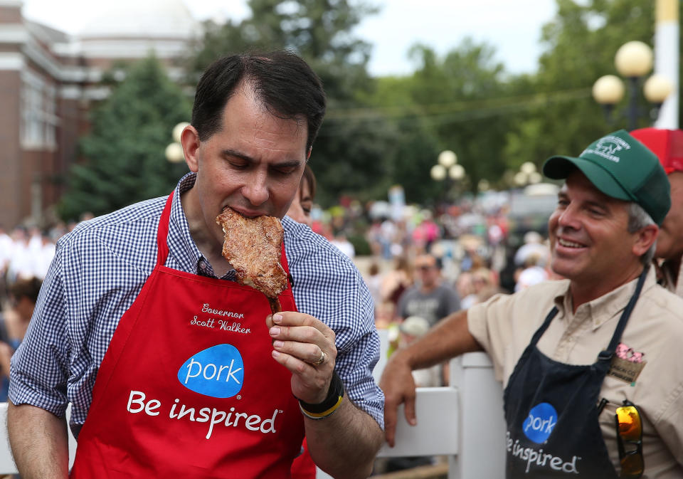 <p>Wisconsin Gov. Scott Walker (R) bites into a pork chop at the Iowa Pork Producers Association stand.</p>