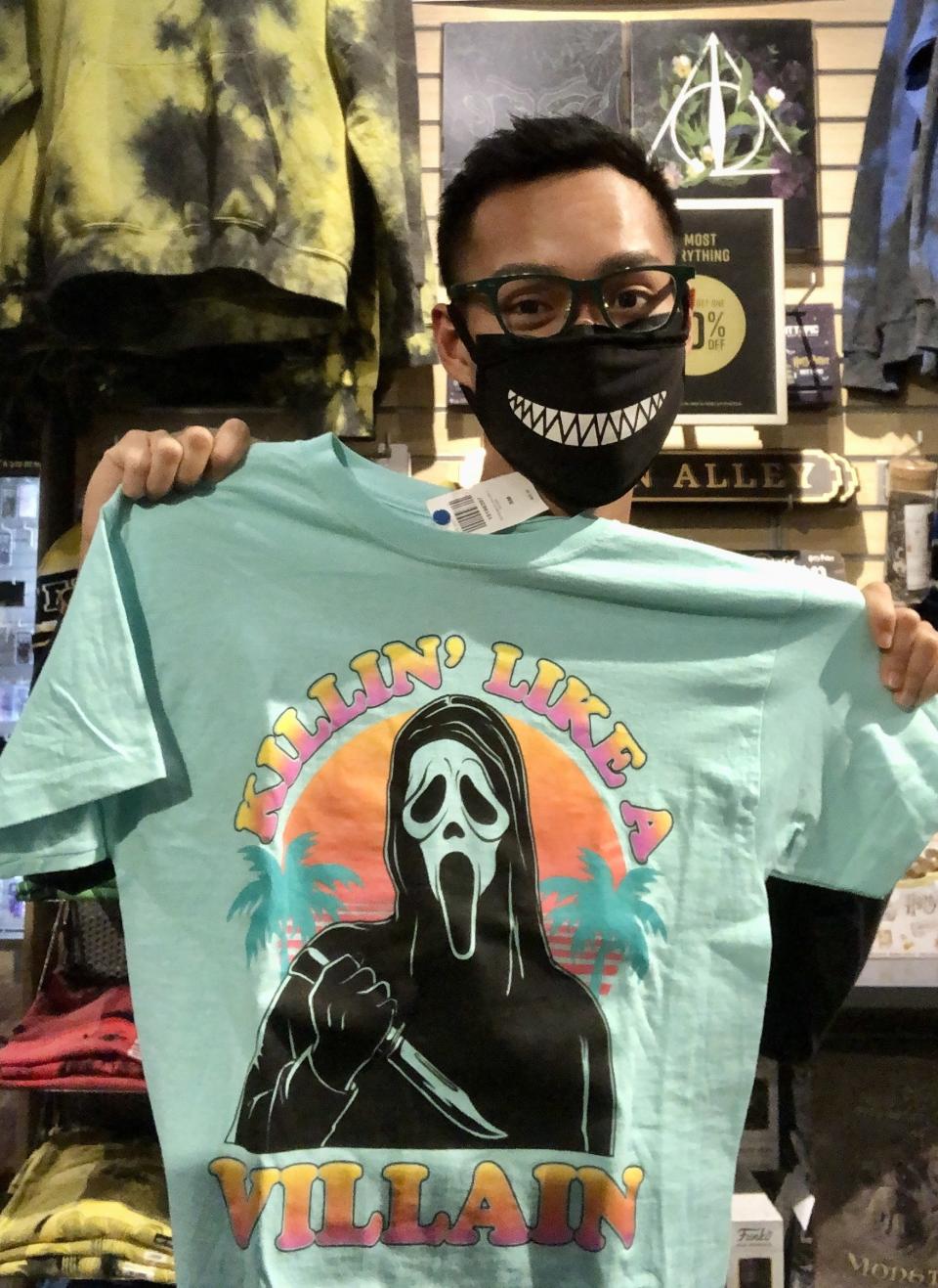 Author holding a "Scream" related shirt with the character Ghostface