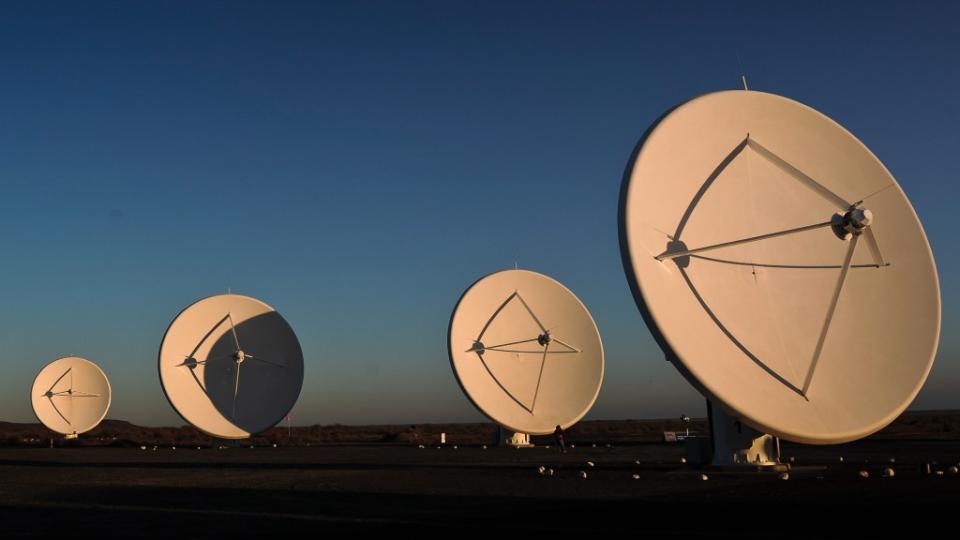 four big radio telescopes sit on a flat plain.