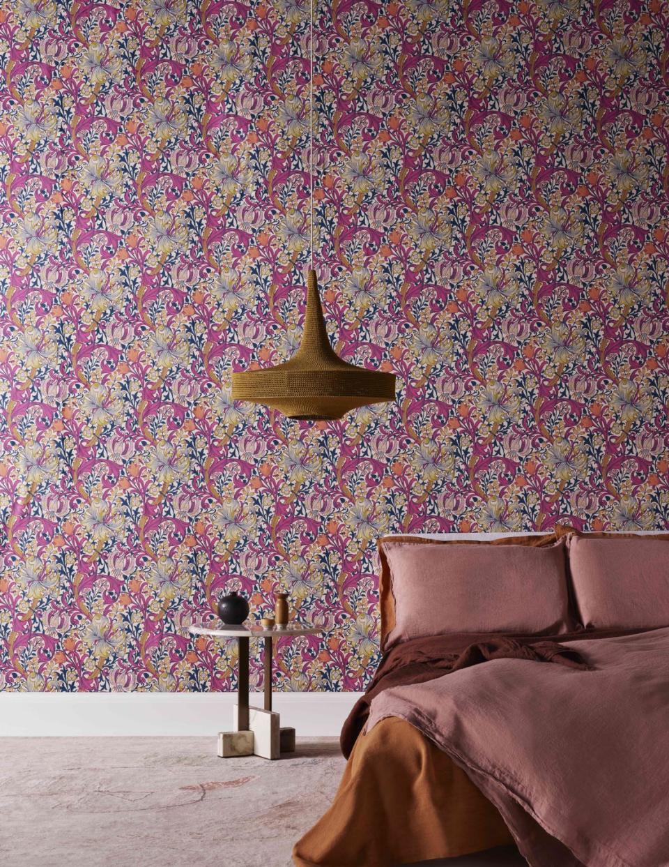 <p>Busy patterns can be conducive to a quiet mind. The tight repeat and on-trend orange/pink colour clash of this ‘Golden Lily’ wallpaper in ‘Pink Fizz’ by Morris & Co could, at first glance, seem like an unusual choice for a bedroom, but for maximalists it’s as peaceful as a bedtime story. Plus, it’s sure to cheer you up when the alarm sounds!</p>