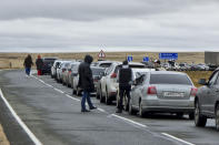 People walk next to their cars queuing to cross the border into Kazakhstan at the Mariinsky border crossing, about 400 kilometers (250 miles) south of Chelyabinsk, Russia, Tuesday, Sept. 27, 2022. Officials say about 98,000 Russians have crossed into Kazakhstan in the week since President Vladimir Putin announced a partial mobilization of reservists to fight in Ukraine. (AP Photo)