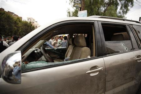 People gather around the car of the Shi'ite politician Ismail al-Wazir after an assassination attempt in Sanaa April 8, 2014. REUTERS/Khaled Abdullah