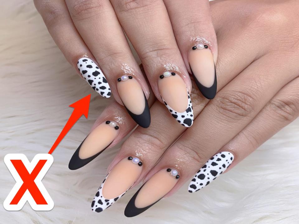 An X pointing at nails with a cow design.