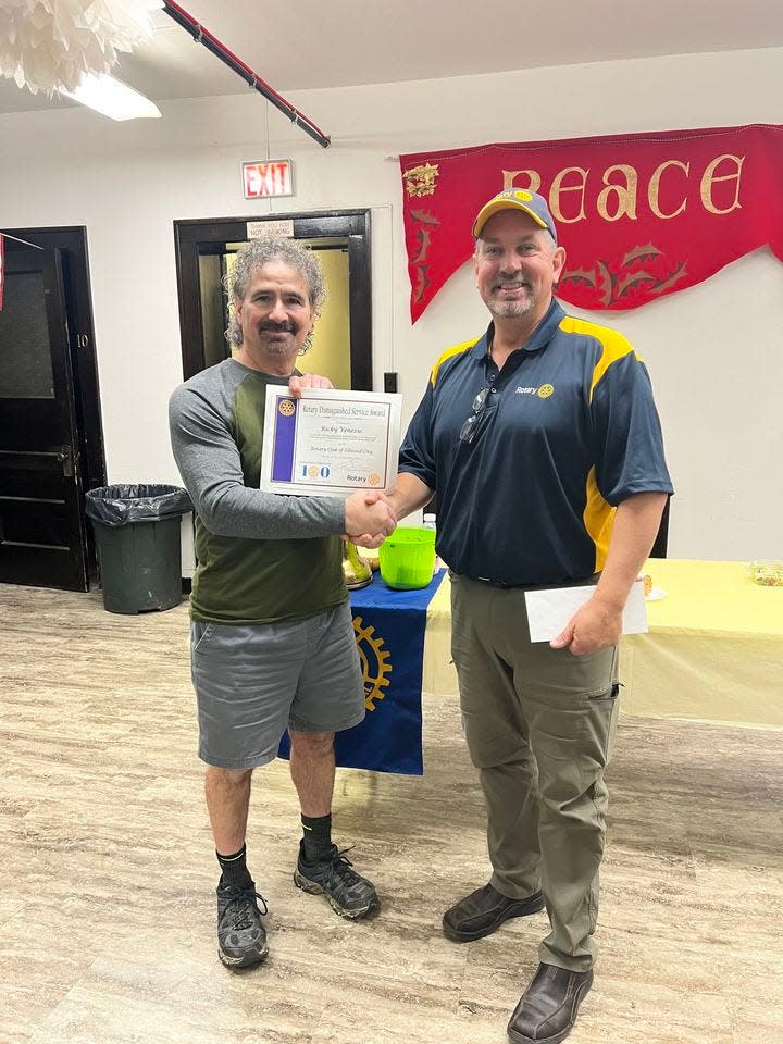 Rick Venezie (left) receives a commendation from Ellwood City Rotary Club President Doug Slade.