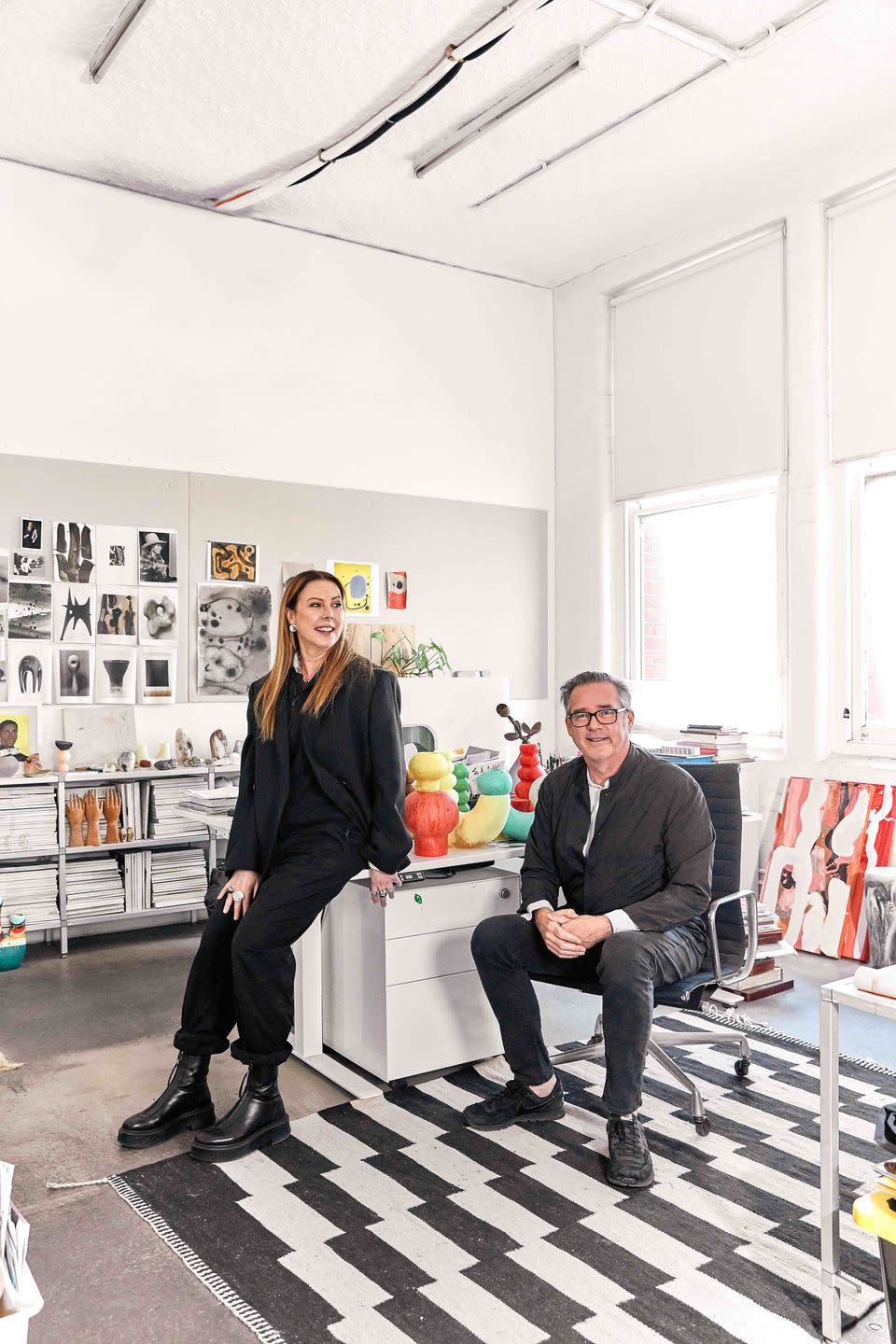 a man and a woman sitting in a room with art on the wall