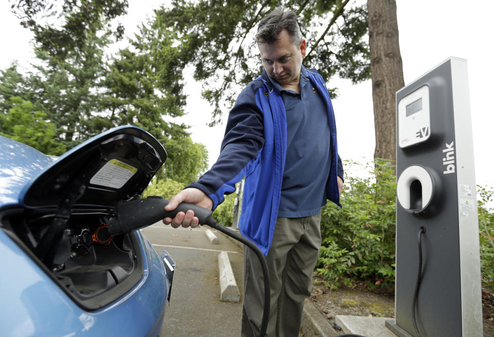 Patrick Conner' shows how to plug his Nissan Leaf electric car at a charging station at the public library in Hillsboro, Ore., Tuesday, May 19, 2015. Fuel-efficient, hybrid and electric cars are a boon for the environment, but their growing popularity means shrinking fuel tax revenues for state coffers and less money to pay for road and bridge projects. Oregon is about to embark on a first-in-the-nation program that aims to address this shortfall by testing the feasibility of taxing motorists not for the fuel they use, but for the miles they drive. (AP Photo/Don Ryan)