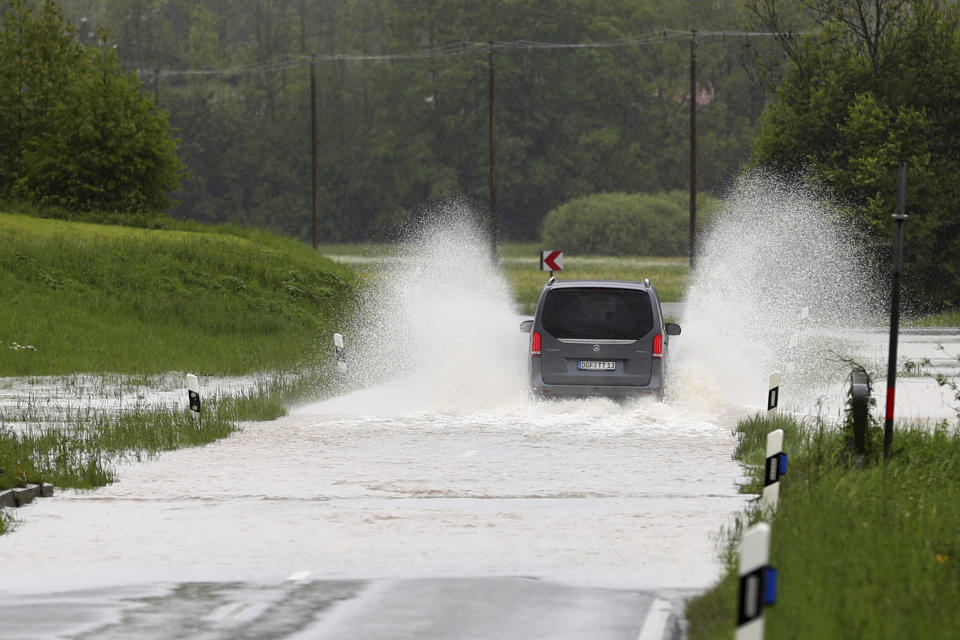 A car makes his way through a flooded road near Marquartstein, Germany, Tuesday, May 21, 2019. (AP Photo/Matthias Schrader)