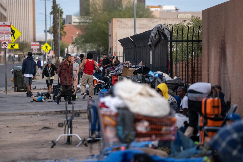 People gather along a sidewalk on Madison Street between 12th and 13th avenues in Phoenix on Feb. 19, 2024.