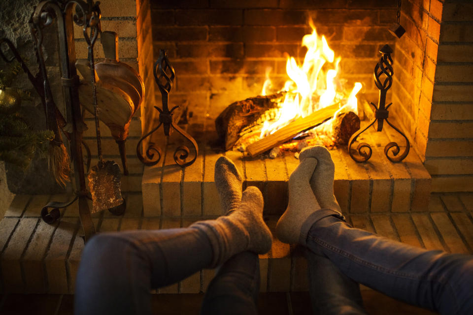 Low section of couple resting by fireplace at home (Cavan Images / Getty Images)