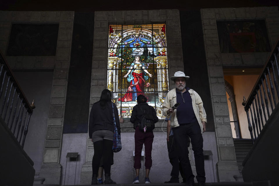 Visitors look at a stained glass titled "La Bienvenida" or The Welcome, inside the former Jesuit college Antiguo Colegio de San Ildefonso in Mexico City, Wednesday, April 26, 2023. The Jesuits arrived in the capital half a century after the Spanish conquest, in 1572, and and few years later they founded San Ildefonso, a school for seminarians and missionaries. (AP Photo/Marco Ugarte)