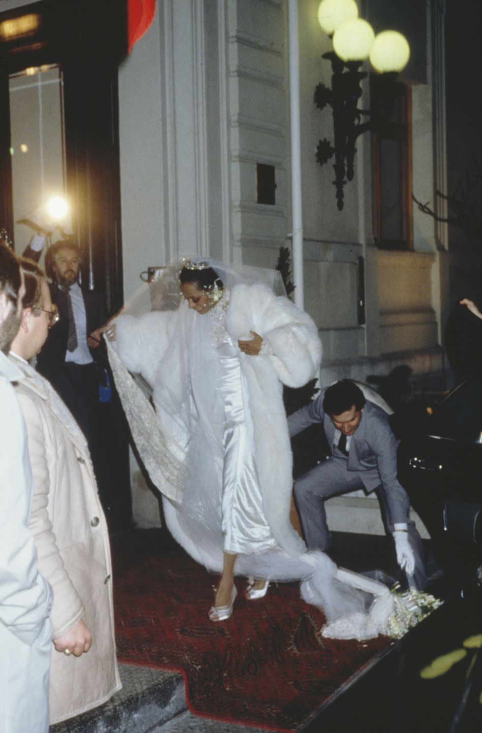 <p>Diana Ross wears a full-length white fur coat to her February nuptials in Romainmotier, Switzerland to Norwegian businessman Arne Naess Jr. The Queen of Motown gets help with her tangled satin and lace dress on her way in.</p>