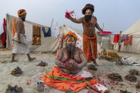 A Hindu Holy man prays as others shower flower petals on him during Magh Mela festival, in Prayagraj, India. Tuesday, Feb. 16, 2021. Hindus believe that ritual bathing on auspicious days can cleanse them of all sins. A tented city for the religious leaders and the believers has come up at the sprawling festival site with mounted police personnel keeping a close watch on the activities. The festival is being held amid rising COVID-19 cases in some parts of India after months of a steady nationwide decline. (AP Photo/Rajesh Kumar Singh)