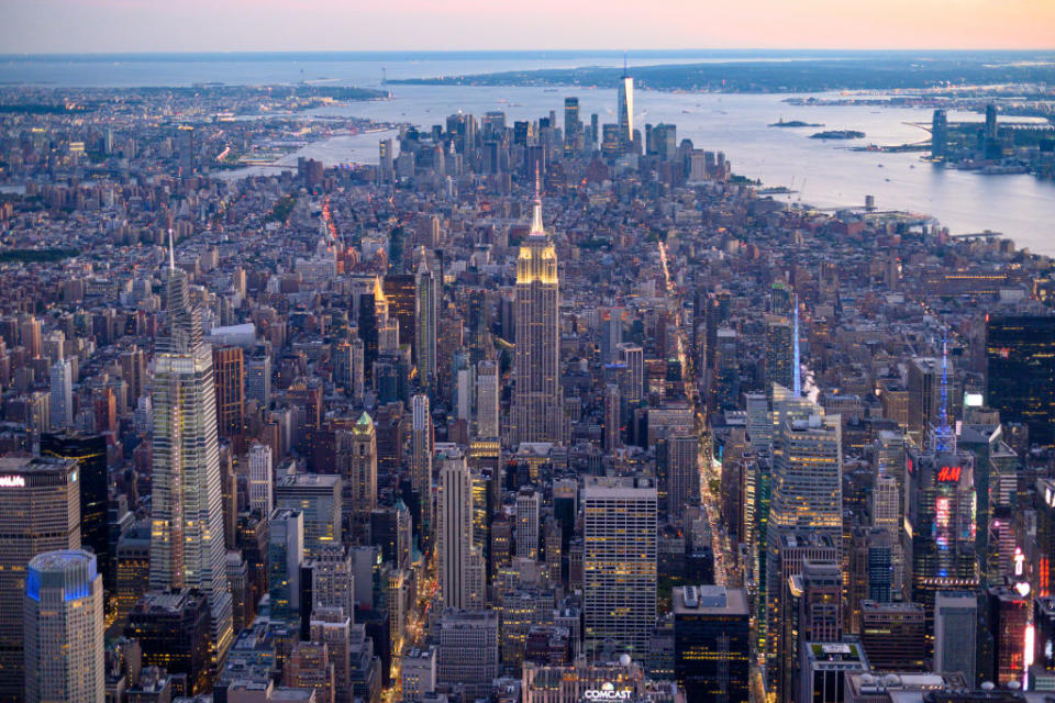 Aerial view of New York City featuring dense skyscrapers, with the Empire State Building prominently in the center and Manhattan in the background