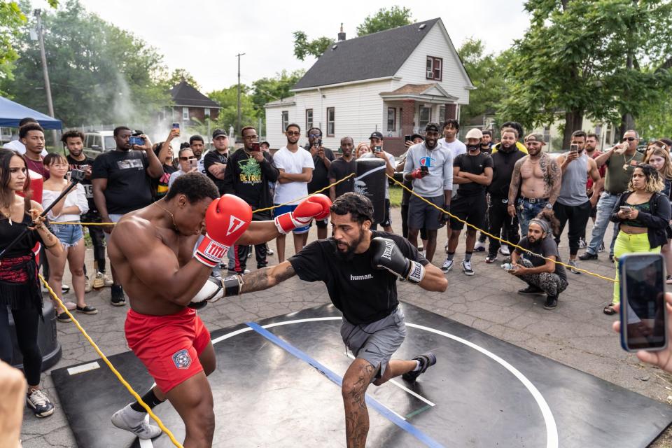 Dwayne Taylor, right, of Lincoln Park, lands a punch on Justin Thomas, of Lincoln Park, as a crowd surrounds a makeshift ring in the street during a Pick Your Poison Detroit event in Detroit's Delray neighborhood on Sunday, June 19, 2021.