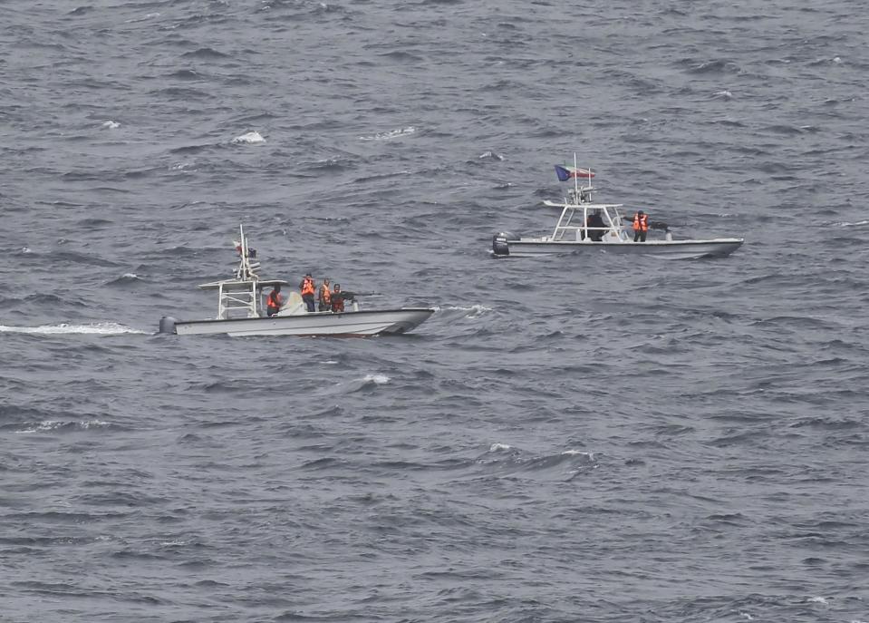 In this Tuesday, March 21, 2017 photograph, members of Iran's paramilitary Revolutionary Guard watch the USS George H.W. Bush as it travels through the Strait of Hormuz. The arrival of the nuclear-powered aircraft carrier to the Persian Gulf marks the first such deployment under new U.S. President Donald Trump. (AP Photo/Jon Gambrell)