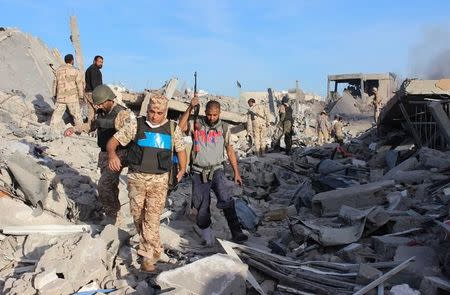 Fighters of Libyan forces allied with the U.N.-backed government walk through debris as they are close to securing last Islamic State holdouts in Sirte, Libya December 5, 2016. REUTERS/Ayman Sahely