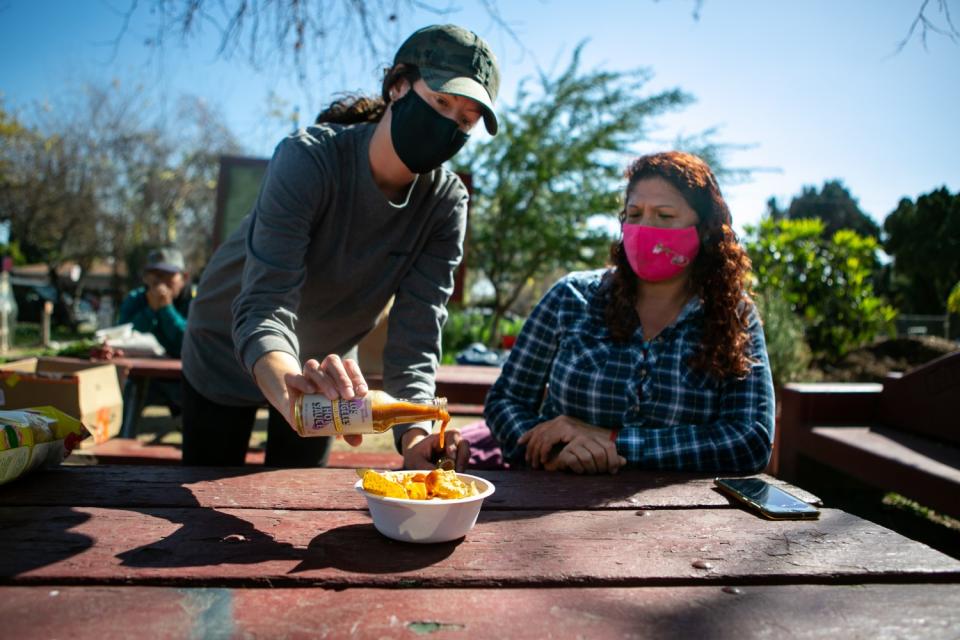 Elizabeth Christy, Program Manager at La Madera Community Garden, pours Small Axe Peppers sauce over some chips