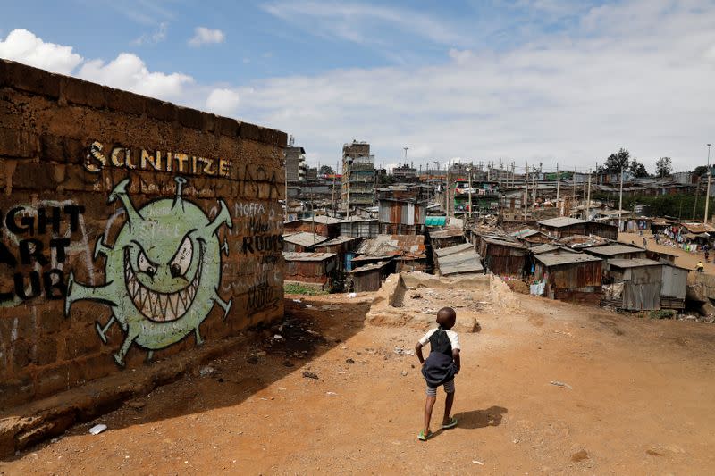 FILE PHOTO: A boy walks in front of a graffiti promoting the fight against the coronavirus disease in the Mathare slums of Nairobi