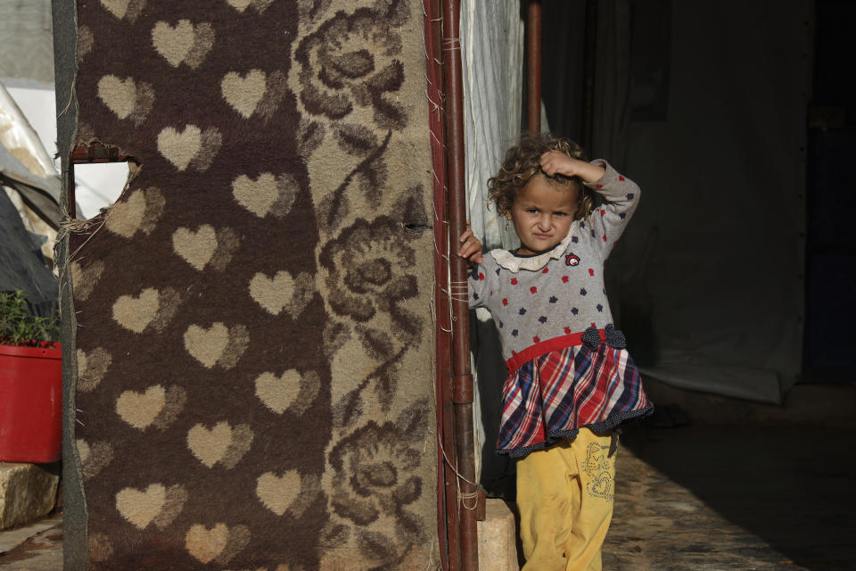 A displaced Syrian child in an encampment in northwestern Syrian stands outside a tent in the village of Harbnoush, Monday, May 13, 2024. Syria's devastating civil war, now in its 14th year, remains largely frozen and so are efforts to find a viable political solution to end it, while millions of Syrians have been pulled into poverty, and struggle with accessing food and health care as the economy deteriorates across the country's front lines. Aid organizations are making their annual pitches to donors ahead of a fundraising conference in Brussels for Syria on Monday, May 27. (AP Photo/Omar Albam)