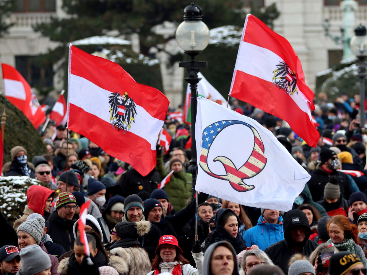 Demonstrators waves Austrian and QAnon flags during a protest against government restriction measures to curb the spread of Covid-19 in Vienna, Austria, on Saturday 16 January 2021 (Ronald Zak/AP)