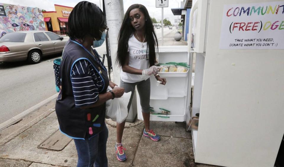 Sherina Jones, center, passes out food from the community refrigerator she set up to feed locals who may be struggling due to the pandemic.