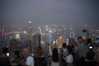 In this Oct. 9, 2019 photo, tourists take photos in a foggy evening at the Victoria Peak in Hong Kong. The body-blow of months of political protests on Hong Kong’s tourism is verging on catastrophic for one of the world’s great destinations. Geared up to receive 65 million travelers a year, the city’s hotels, retailers, restaurants and other travel-oriented industries are suffering. But some intrepid visitors came specifically to see the protests and are reveling in deep discounts and unusually short lines at tourist hotspots.(AP Photo/Felipe Dana)