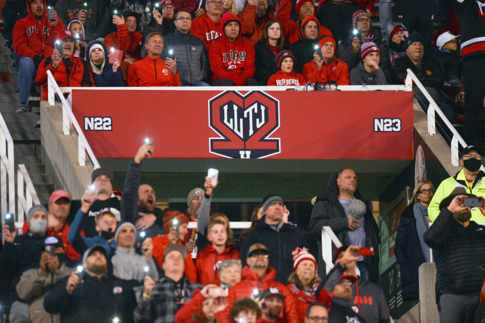 Utah fans shine their phone flashlights after the third quarter of a game in 2021 in memory of football players Aaron Lowe and Ty Jordan.