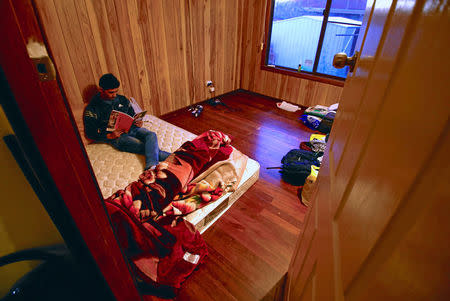 Ali Rasooli, a refugee from Afghanistan, sits on his mattress reading a book in a house he rents with other refugees, in the western Sydney suburb of Guildford, Australia, July 17, 2016. REUTERS/David Gray