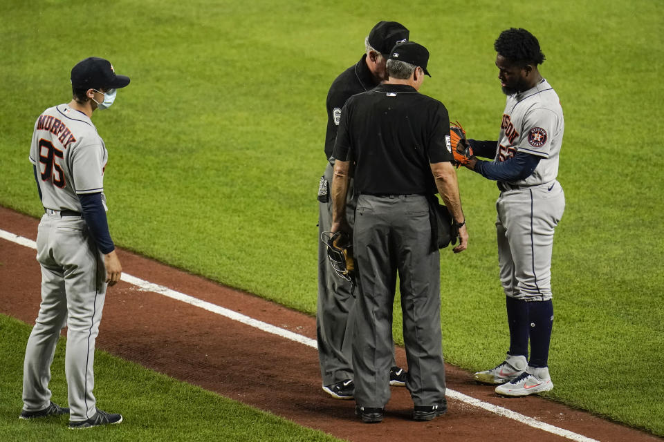 Houston Astros assistant pitching coach Bill Murphy, left, looks on as relief pitcher Cristian Javier has his gear inspected by first base umpire Ted Barrett, back left, and home plate umpire Angel Hernandez during the sixth inning of a baseball game, Monday, June 21, 2021, in Baltimore. (AP Photo/Julio Cortez)