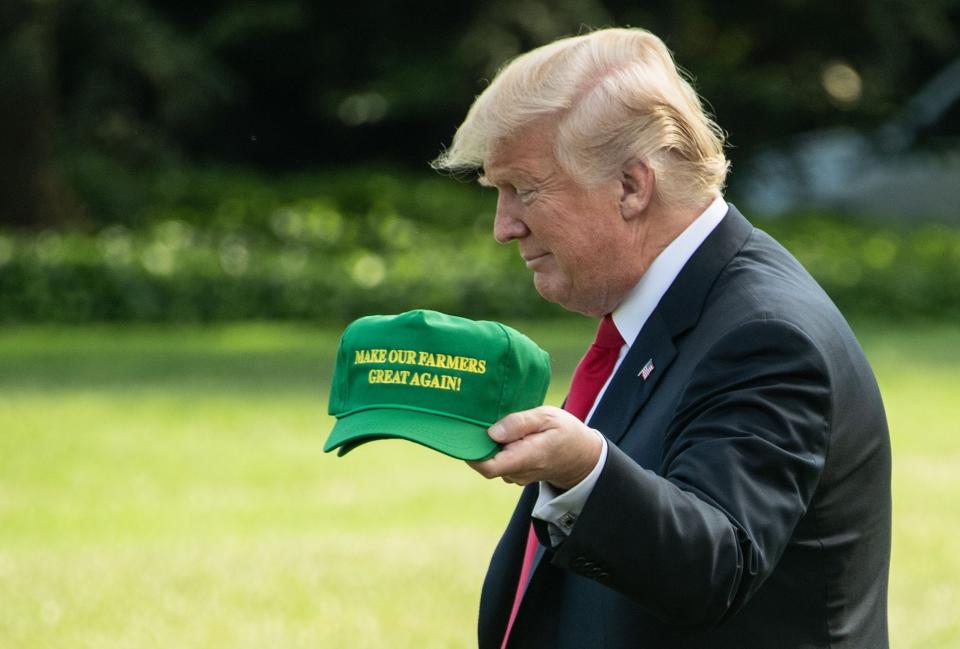 President Donald Trump displays caps reading "Make our Farmers Great Again!" in 2018