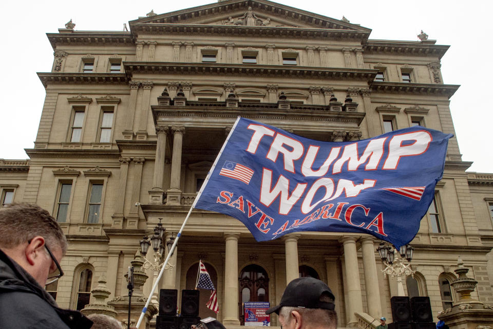 FILE - A protester waves a Trump flag during rally organized by a group called Election Integrity Fund and Force at the Michigan State Capitol, Tuesday, Oct. 12, 2021, in Lansing, Mich. Michigan Attorney General Dana Nessel has charged 16 Republicans Tuesday, July 18, 2023, with multiple felonies after they are alleged to have submitted false certificates stating they were the state’s presidential electors despite Joe Biden’s 154,000-vote victory in 2020. The group includes Republican National Committeewoman Kathy Berden and Meshawn Maddock, former co-chair of the Michigan Republican Party. (Jake May/The Flint Journal via AP, File)