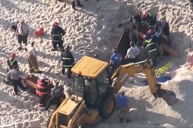 Rescue crews try to free two teenagers from a 10-foot hole in the beach that collapsed on them Tuesday in Toms River, N.J. (NBC Philadelphia)