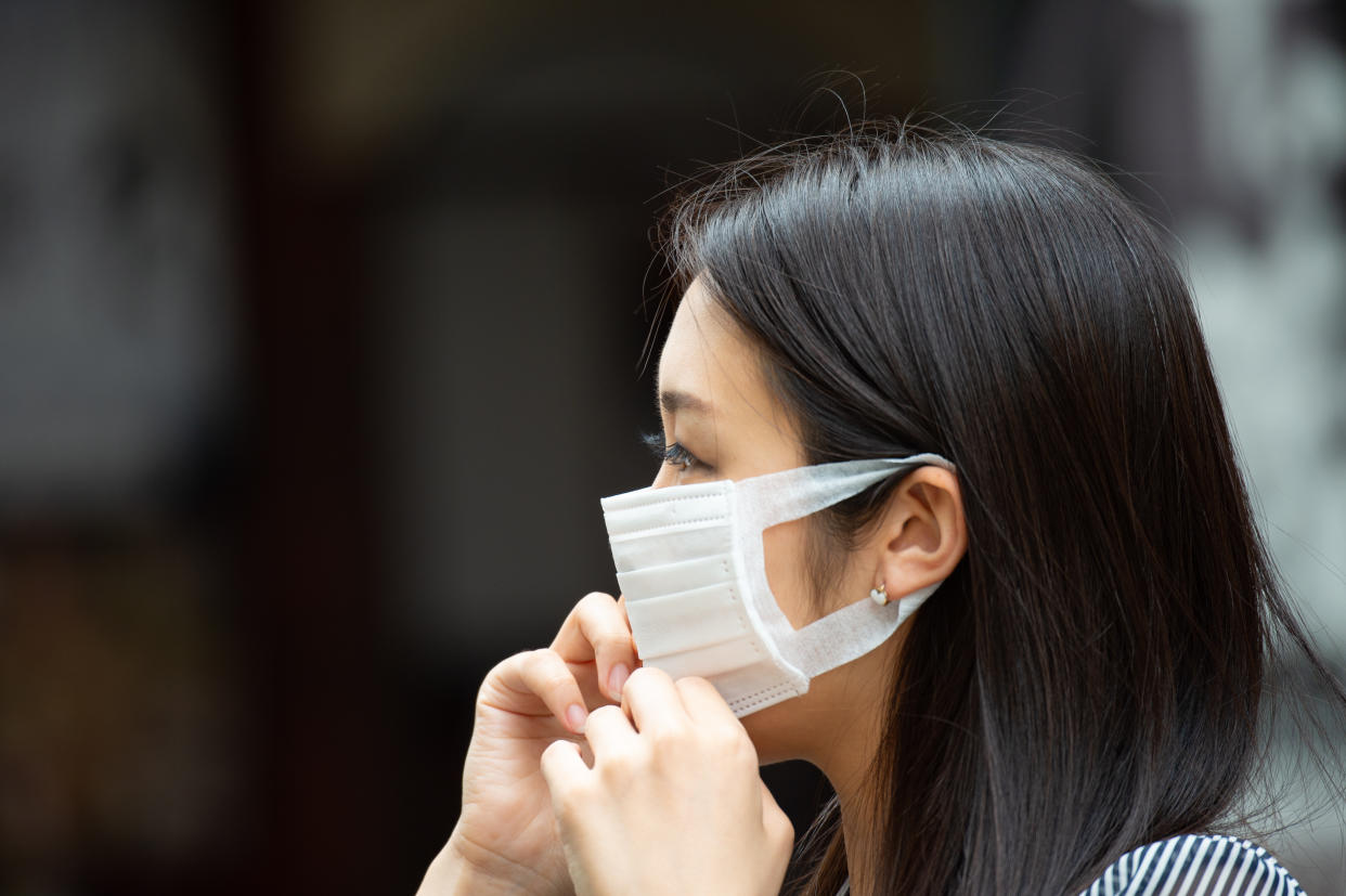 Asian woman putting on face mask