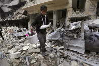 FILE - A man walk past destruction by airstrikes on the town of Ariha, in Idlib province, Syria, Jan. 30, 2020. Political observers say Russia’s brazen Syria intervention emboldened Putin, giving him a renewed Middle East foothold and helped pave the way for his current attack on Ukraine. (AP Photo/Ghaith Alsayed, File)