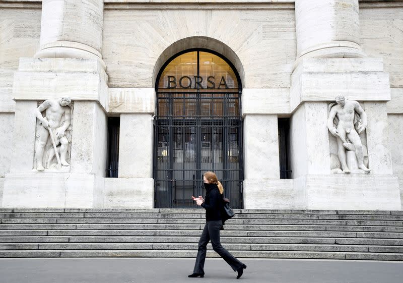 FILE PHOTO: A woman passes the Italian Stock Exchange in Milan
