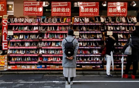 A woman looks at shoes on sale at an outlet store in Tokyo's shopping district