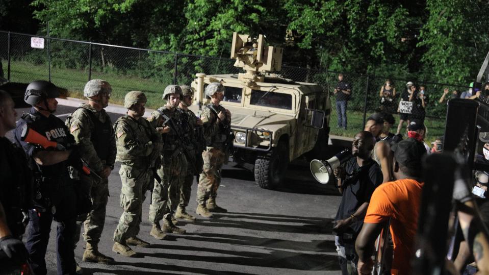 Protesters stand off with members of the Missouri National Guard in Florissant, Mo., Sunday, June 7, 2020. A suburban St. Louis police detective has been suspended after a video appears to show him hitting a man with a police SUV and then hitting the suspect at least twice while arresting him. Florissant Police Chief Tim Fagan has asked St. Louis County police and the FBI to investigate. (Christian Gooden/St. Louis Post-Dispatch via AP)