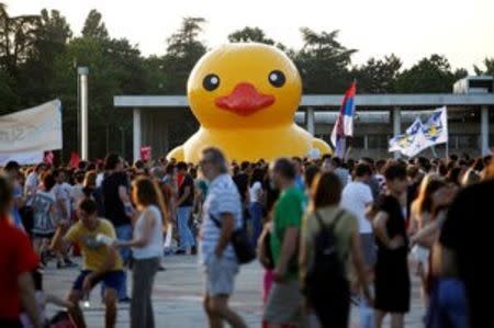 Protesters with flags walk past a rubber duck, which is a symbol of protest against the Belgrade Waterfront project, in Belgrade, Serbia, June 25, 2016. REUTERS/Djordje Kojadinovic