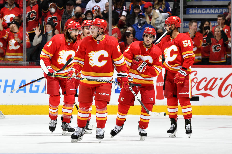 CALGARY, ALBERTA - FEBRUARY 12: Elias Lindholm #28, Johnny Gaudreau #13 and teammates of the Calgary Flames celebrate a goal against the New York Islanders at Scotiabank Saddledome on February 12, 2022 in Calgary, Alberta. (Photo by Terence Leung/2022 NHLI)