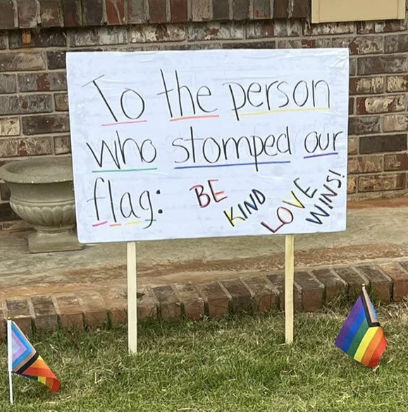 Sign with Pride color highlights: "To the person who stomped our flag: Be kind, love wins!"