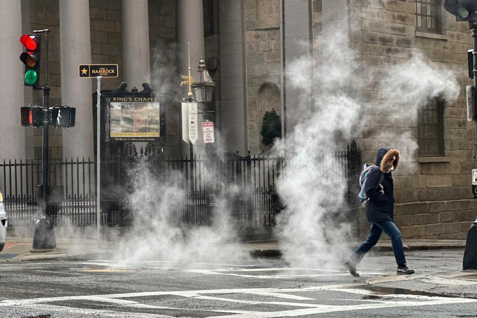 A pedestrian walks through downtown Boston during a rain storm, Wednesday, April 3, 2024. A nor'easter has brought heavy wind, rain and snow to New England. (AP Photo/Robert F. Bukaty)