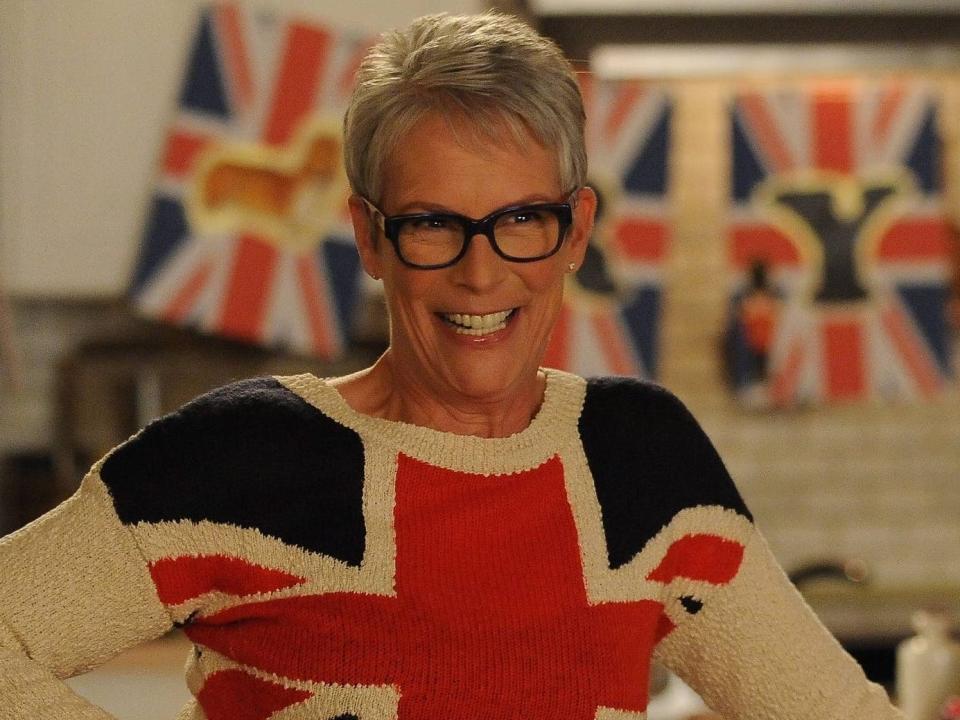 Jamie Lee Curtis as Joan wearing a sweater with British flag design and British flag banners in background