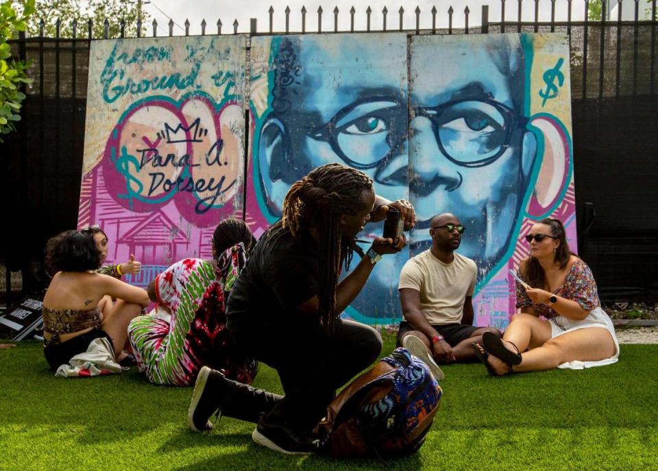 Photographer Soils Minor, 37, snaps a shot of festivalgoers in front of a mural of D.A. Dorsey, who was considered the first Black millionaire in Miami, during AFROPUNK music festival at The Urban in the Historic Overtown neighborhood of Miami, Florida, on Saturday, May 21, 2022.