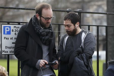 People listen and watch on their mobile devices as Scotland's First Minister Nicola Sturgeon demands a new independence referendum to be held in late 2018 or early 2019, once the terms of Britain's exit from the European Union have become clearer, outside Bute House, in Edinburgh, Scotland, Britain March 13, 2017. REUTERS/Russell Cheyne