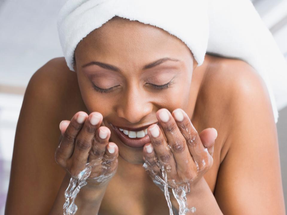 African American woman washing face - stock photo