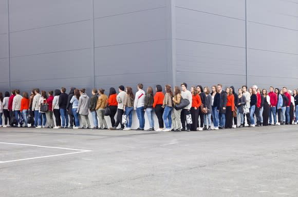 People waiting in line outside of a  store.