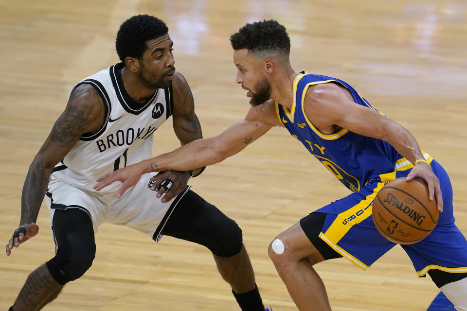 Golden State Warriors guard Stephen Curry, right, drives against Brooklyn Nets guard Kyrie Irving during the first half of an NBA basketball game in San Francisco, Saturday, Feb. 13, 2021. (AP Photo/Jeff Chiu)