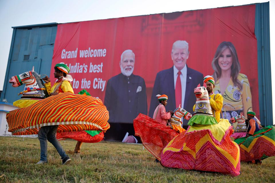 Indian folk dancers rehearse their performance next to a billboard featuring Indian Prime Minister Narendra Modi, U.S. President Donald Trump and first lady Melania Trump at the airport in Agra, India, Sunday, Feb. 23, 2020.