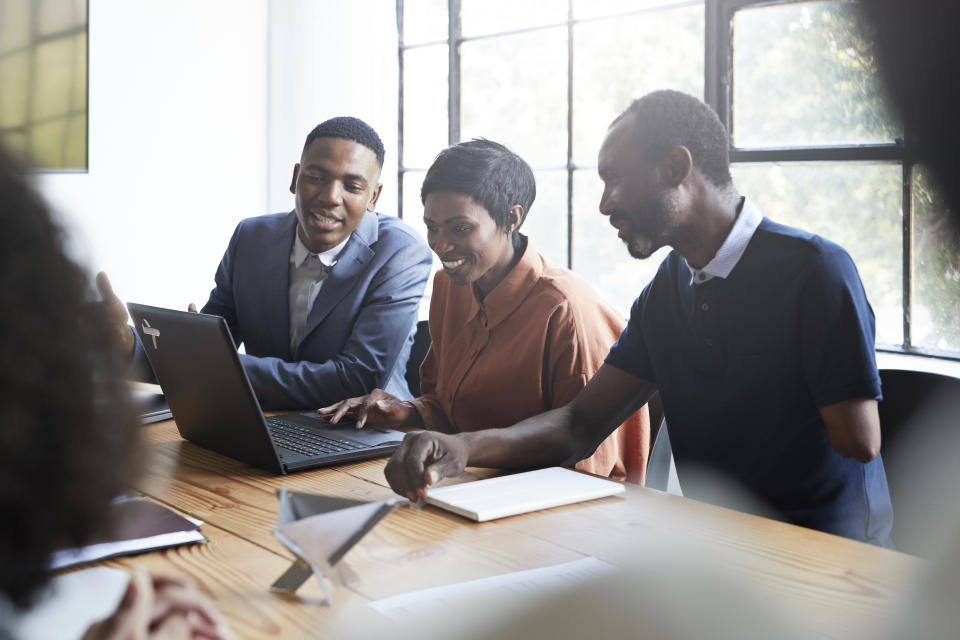 Smiling female and male entrepreneurs sitting in conference room during business meeting at workplace