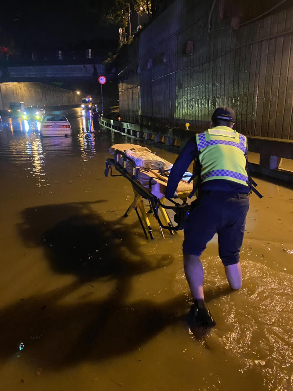 豪雨來襲，苗栗縣消防局20日表示，苗栗市國華地下道積水嚴重時逼近20公分，一度暫時封閉，有休旅車冒險涉水通過時受困，車上人員腹痛，消防人員冒雨推擔架進入，協助駕駛送醫。（圖／苗栗縣消防局提供）